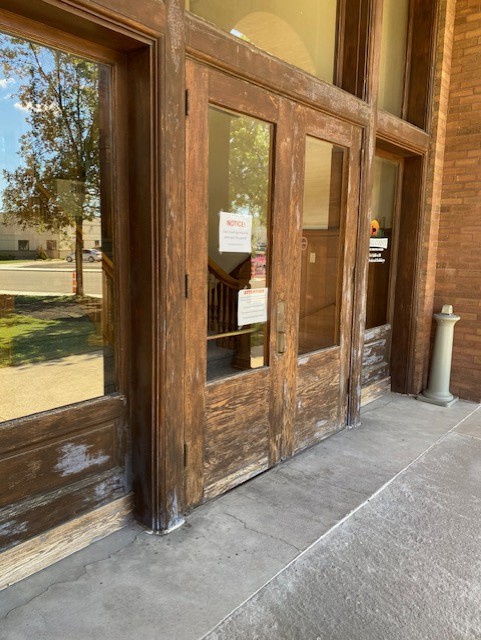 Weathered wood entry doors of a historic brick building before restoration